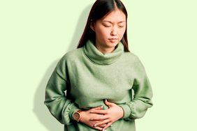 Woman with a stomach ache on a green background