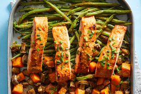 sheet pan of salmon and vegetables on blue background