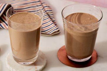 two tall glasses filled with a light brown smoothie
