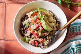 Overhead view of a white bowl of Black Bean-Quinoa Bowl recipe on a reddish brown tile tabletop
