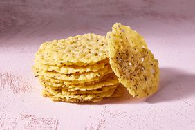 Side view of a stack of crisps from Parmesan Crisps recipe on a pink textured surface