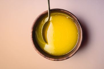a photo of clarified butter in a wooden bowl with a spoon mixing it