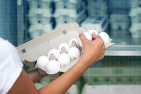 a photo of a woman holding a carton of eggs and examining them