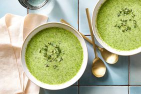 Pureed broccoli soup in a white bowl with a golden spoon on its right side