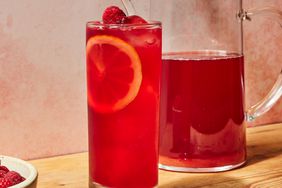 a recipe photo of the Raspberry Iced Tea poured in a glass and a pitcher full of the Raspberry Iced Tea