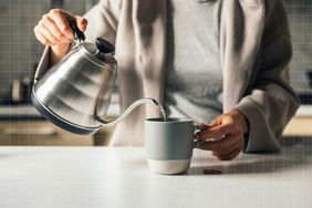 a photo of someone pouring a kettle of boiled water over a cup of tea