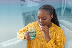 a photo of a woman taking a supplement with a glass of water